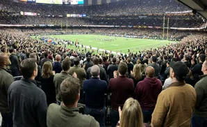 Spectators in a packed stadium watch a football game on a green field.