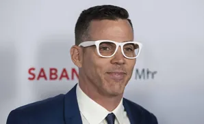 Steve-O wearing white-rimmed glasses and a blue suit.