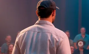 Man in a baseball cap and light-colored shirt facing away from the camera, addressing a blurred audience.