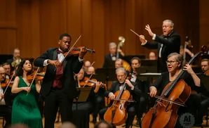 An orchestra performs, with a violinist and cellist in focus, and a conductor leading.