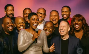 A diverse group of ten people, men and women, smile and laugh together for a photo.
