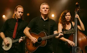 A band of three plays instruments on a dark stage with warm lighting.