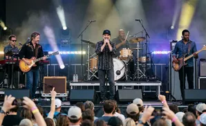 A band performs on stage with colorful lights and smoke.