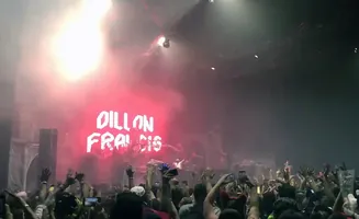 A concert crowd with hands raised under a bright stage light, with 