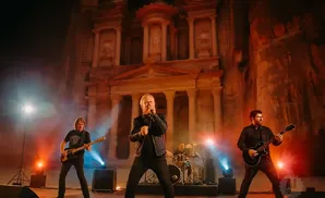 A rock band performs in front of the Treasury at Petra, Jordan, with dramatic lighting.