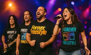 Four performers on stage, two singing into microphones, wearing t-shirts with 
