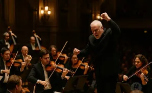 An orchestra conductor with white hair leads musicians playing violins, cellos, and other instruments.
