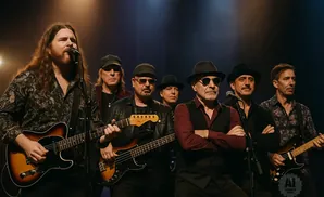 A band of six men on stage, most wearing hats, playing instruments under dim stage lighting.
