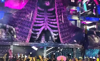 DJ performing on stage inside a giant ribcage structure at a festival.