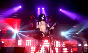 Paul Stanley of KISS performs on stage with a guitar and elaborate makeup.