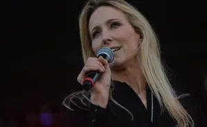 Woman with blonde hair speaking into a microphone.