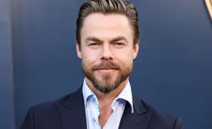 A man with styled hair and a beard smiles at the camera.