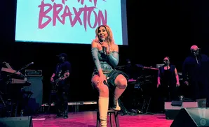 Singer Tamar Braxton performs on stage with a band behind her.