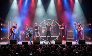 A group of performers on stage with a BMX bike, hoops, and a basketball.