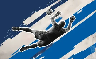 Goalkeeper dives to catch a soccer ball against a backdrop of blue and white stripes.