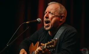 Man singing and playing guitar into a microphone.