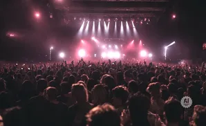 A large crowd at a concert with bright pink and white stage lights.
