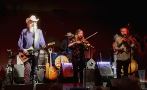 A band performs country music on a dimly lit stage.
