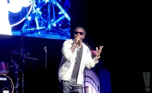 Rapper Gucci Mane performing on stage wearing sunglasses and a white jacket with black pants.