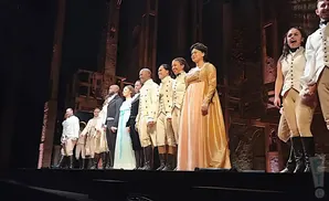 Cast of Hamilton takes a bow on stage in period costumes.