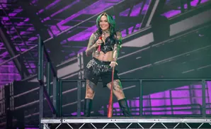 Singer Kehlani performs on stage, holding a red microphone and a baseball bat.