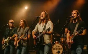 A band performs on stage with four guitarists and a drummer.
