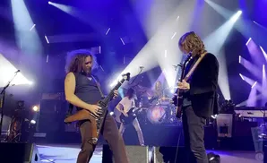 Band performing on stage with bright blue and white spotlights.