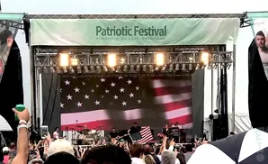A band performs on stage in front of a giant American flag at the Patriotic Festival in Virginia Beach, Virginia.