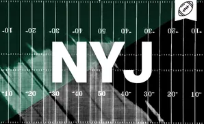 American football field from above, split between dark green and black, with yard lines and numbers.