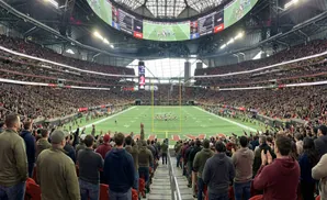 Panoramic view of a packed American football stadium, with fans in the stands watching a game on the field.