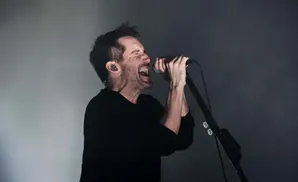 A man singing into a microphone with his eyes closed and mouth open.