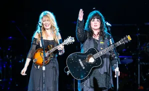 Two women on stage, one plays a mandolin and the other plays a guitar decorated with stars.