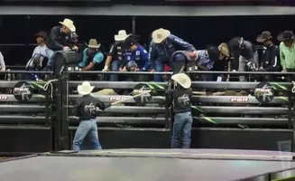 Rodeo riders in cowboy hats stand inside a bucking chute, preparing for a bull ride.