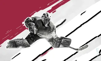 Black and white image of a hockey goalie in mid-air, blocking a shot.