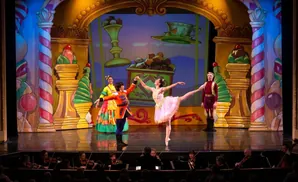 Ballet dancers on a candy-themed stage with an orchestra in the foreground.