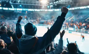 Fans cheer with fists raised at a hockey game.