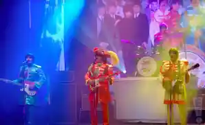 rain performing on stage dressed up as the beatles.
