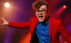 A man in a red suit and blue shirt with glasses shouts excitedly.