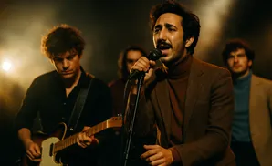 A band performs on stage, with the lead singer in the foreground singing into a microphone.