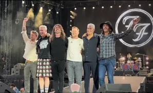 Foo Fighters band members pose on stage with arms around each other.