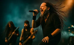 Jonathan Davis of Korn performs live, singing into a microphone with his dreadlocks flying.