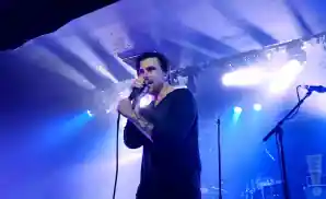 saosin vocalist singing on stage in front of blue lights.