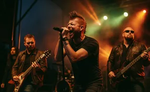 A male rock band performing on stage with a lead singer, guitarist, and bassist under stage lights.