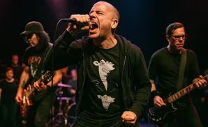 A male singer yells into a microphone on stage with his band.