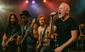 A rock band performs on stage, with the lead singer front and center, singing into a microphone.