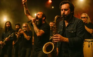 A band performs live music, with a lead singer belting into a microphone and a man playing a saxophone.
