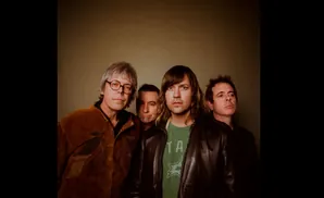 A band plays guitars on stage, with a lead singer belting into a microphone.