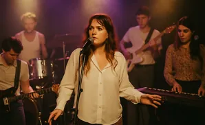 A band performs on a dimly lit stage, with a female singer center stage in front of a microphone.