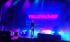 yellowcard playing live on stage with their name on screen behind them