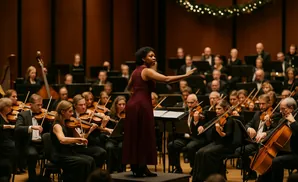 Conductor leads an orchestra, featuring musicians with violins and cellos, with festive lights in the background.